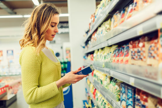 young woman in grocery store reading nutrition labels, nutritional consulting
